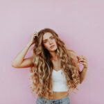 Woman with long hair against pink background.
