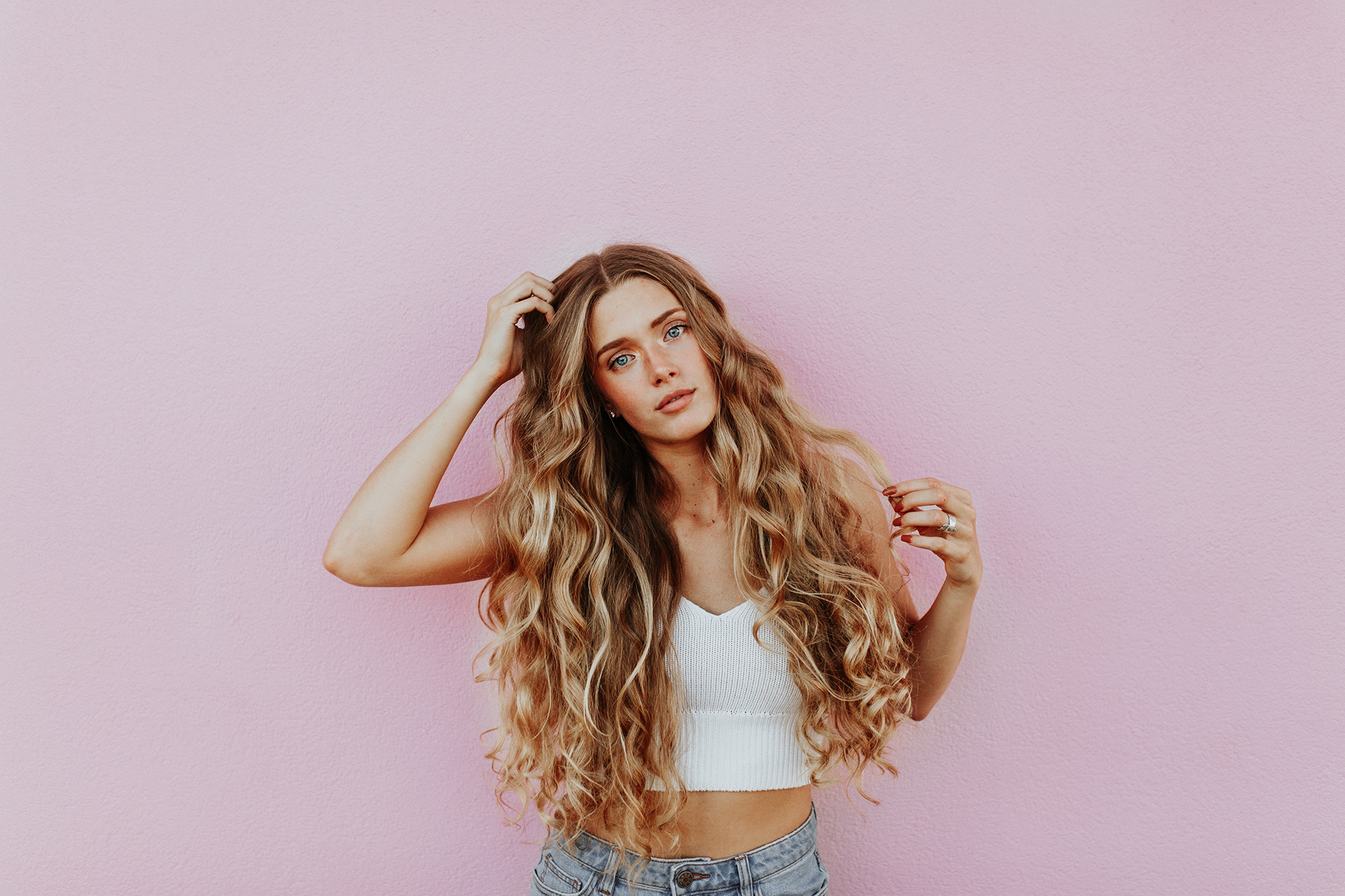 Woman with long hair against pink background.
